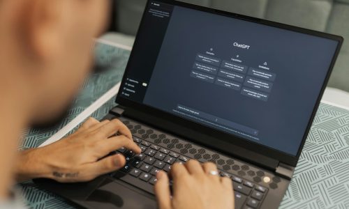 Close-up of a person typing on a laptop displaying the ChatGPT interface, emphasizing modern technology use.