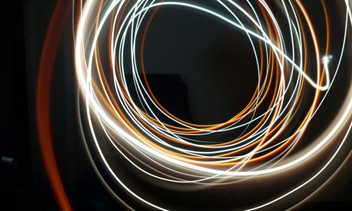 Dynamic long exposure shot of swirling light streaks creating an abstract pattern on a dark background.