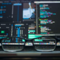 Eyeglasses reflecting computer code on a monitor, ideal for technology and programming themes.